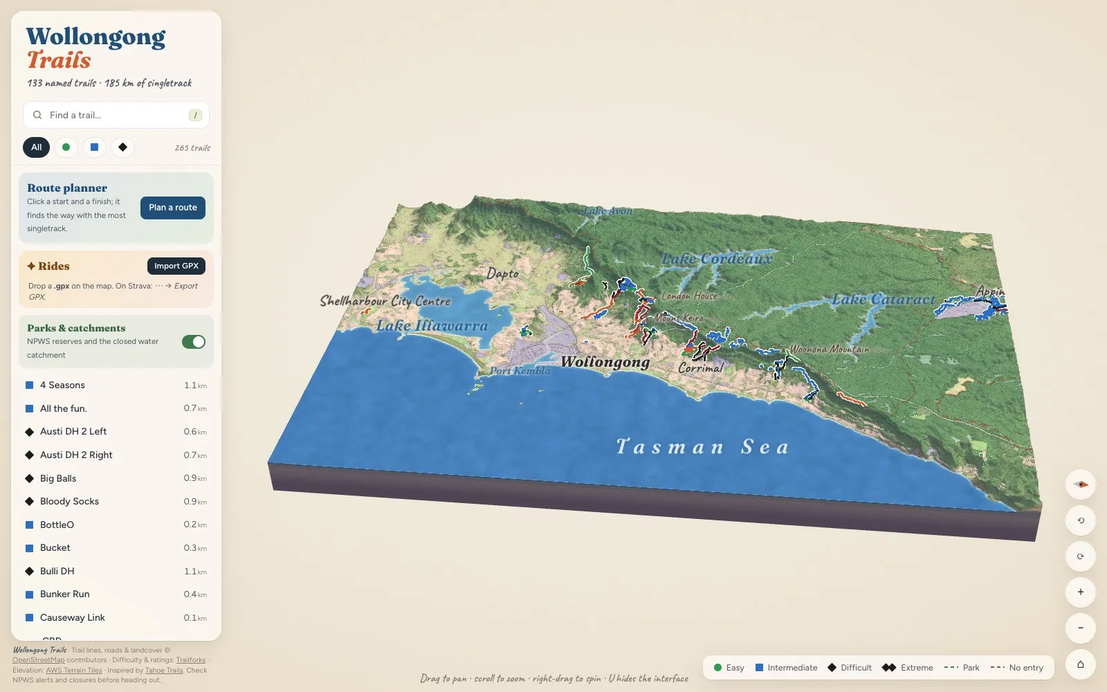 The Illawarra as a painted 3D diorama, from Lake Illawarra and Wollongong up the escarpment to Lake Cordeaux and Lake Cataract, with the mountain bike trails marked in colour and the Tasman Sea in front.